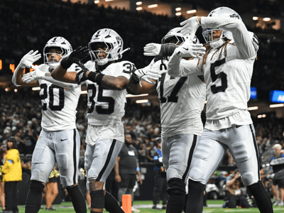 A group of football players celebrating a play in black and white uniforms